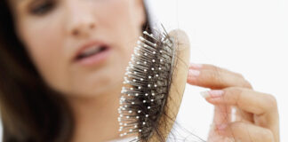 Zaustavite gubitak kose tokom jeseni! Otkrivamo prirodne metode koje stvarno djeluju! Žena drži četku s opalom kosom, ilustracija problema opadanja kose tokom jesenjih mjeseci.